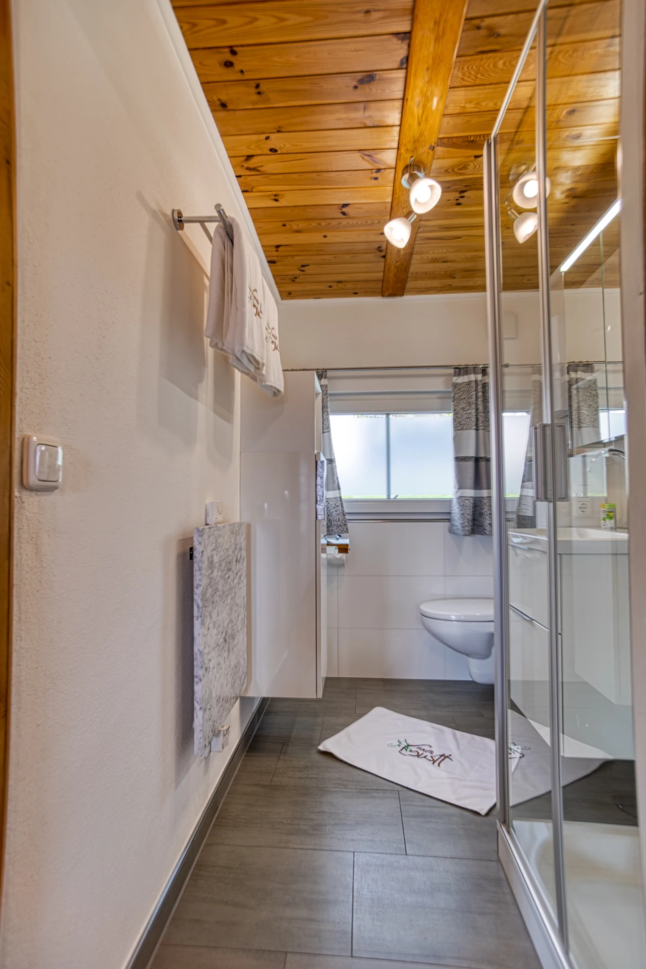 Badezimmer im Ferienhaus mit Spiegel, Handtuchheizung und Duschkabine