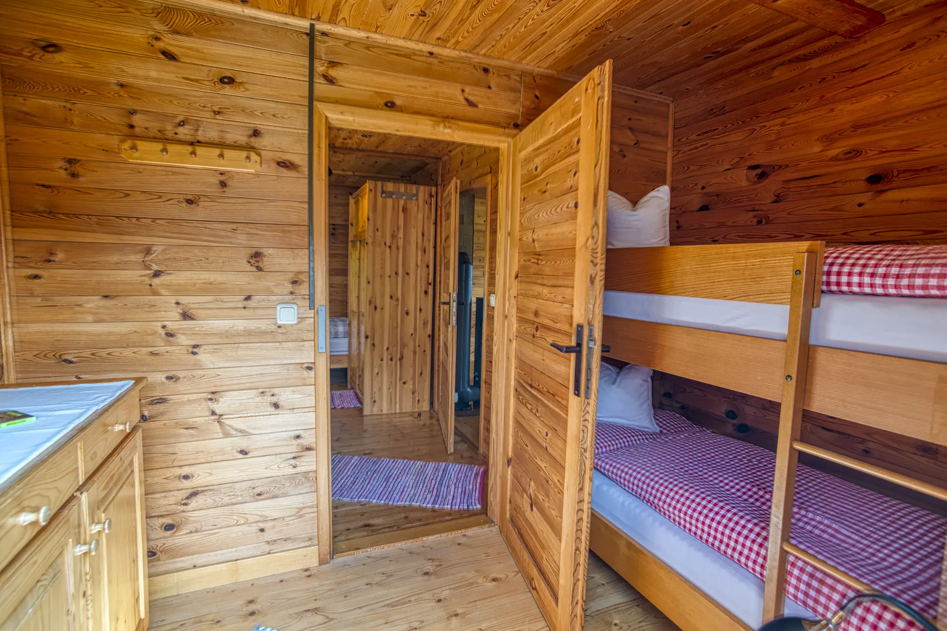 Dreibettzimmer mit Holzwänden und Etagenbett im Ferienhaus Gustl