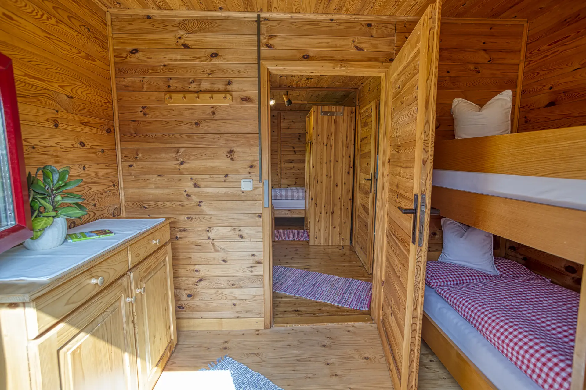 Blick ins Dreibettzimmer mit Fenster und Holzkommode im Ferienhaus Gustl