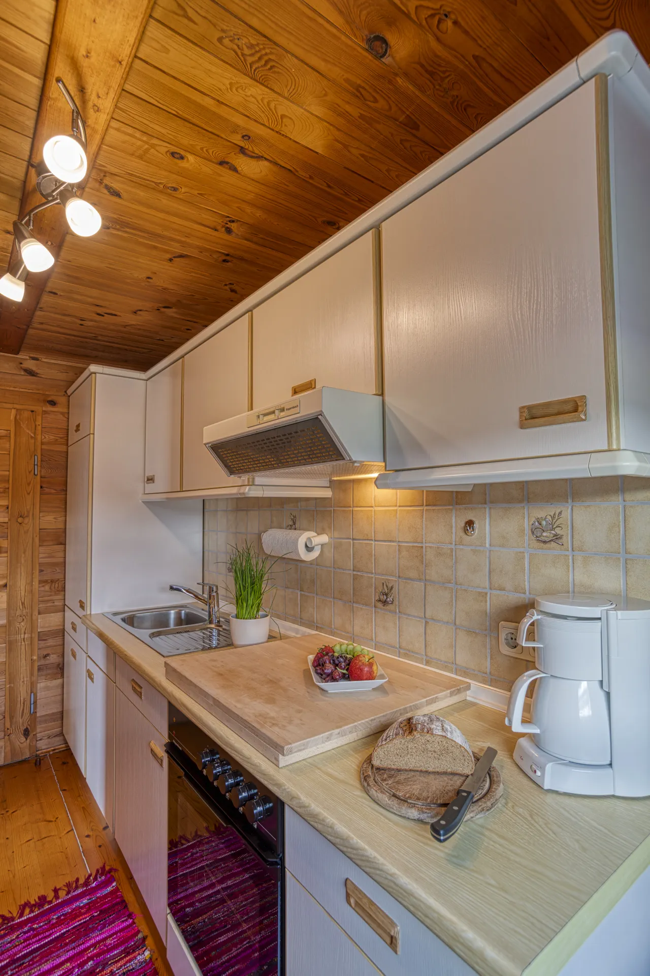 Komplett ausgestattete Küche mit Esstisch und Blick auf den Holzofen