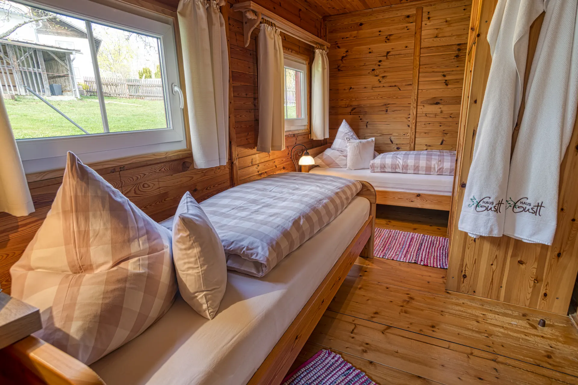 Schlafzimmer mit zwei Einzelbetten, hellem Holzinterieur und Blick in den Garten