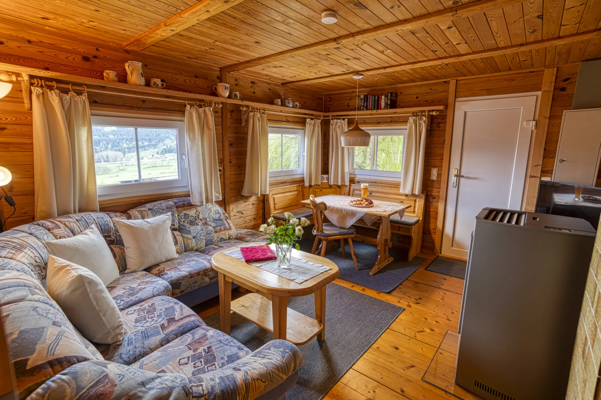 Wohnzimmer mit Couchgarnitur, Kachelofen und Essecke im Landhausstil