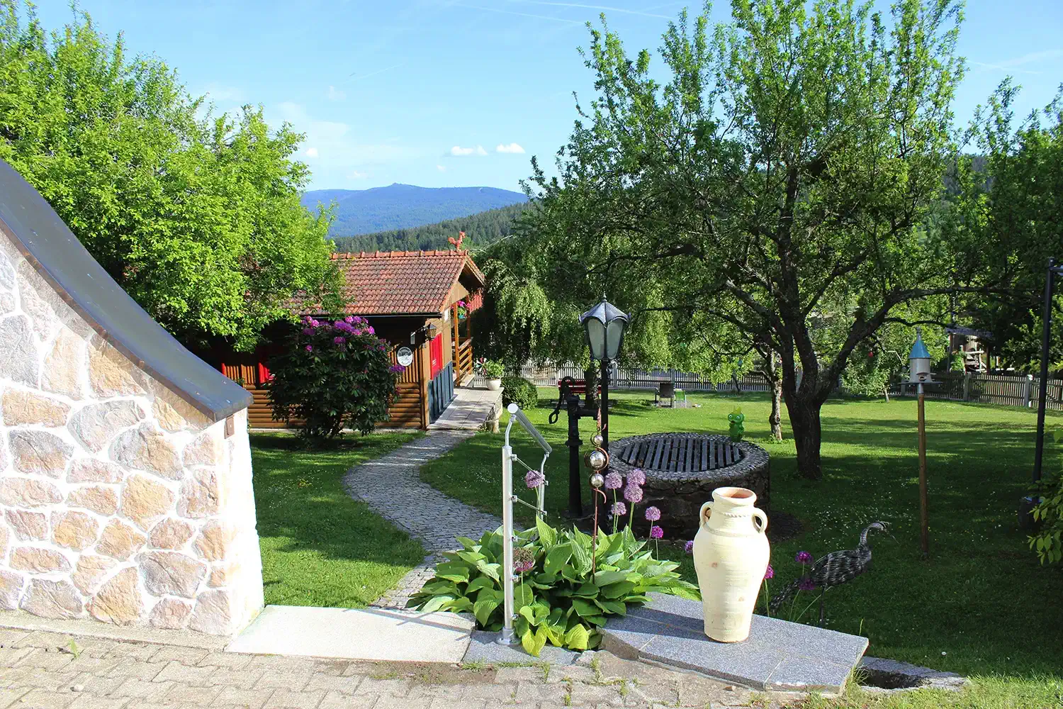 Gartenblick mit Weg und Brunnen vor dem Ferienhaus Gustl